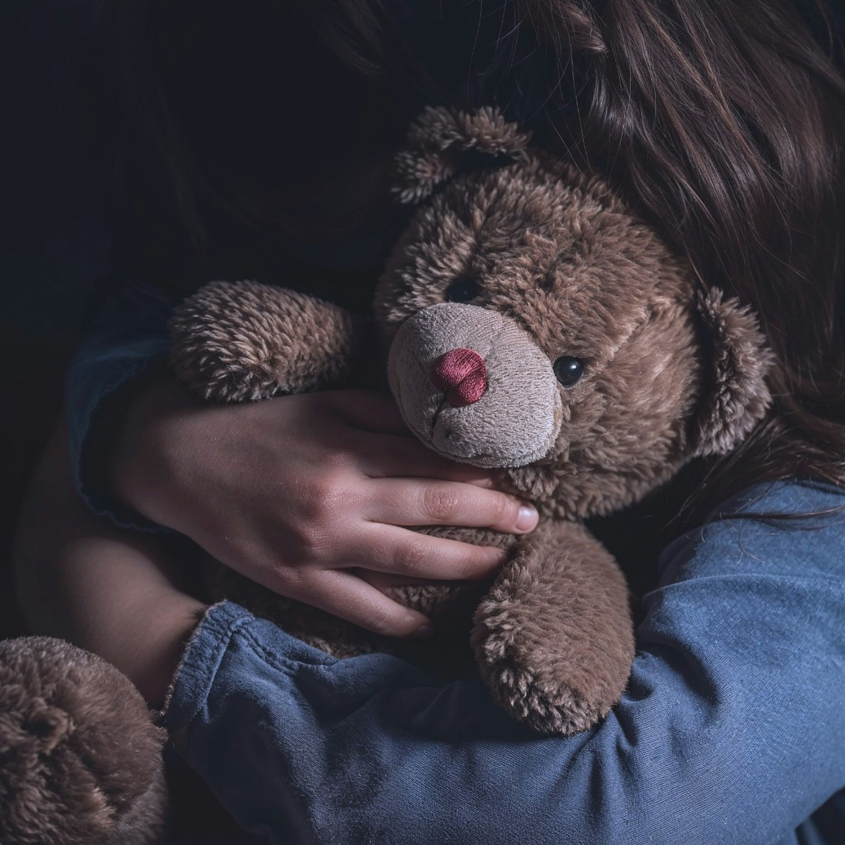 moody photo of a child holding teddy bear