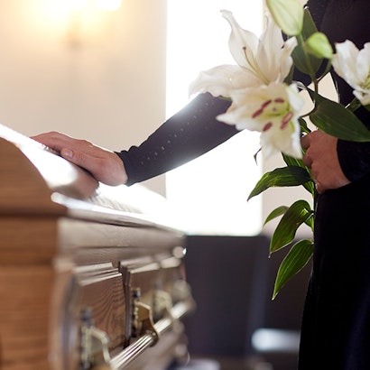 a woman placing her hand on a casket