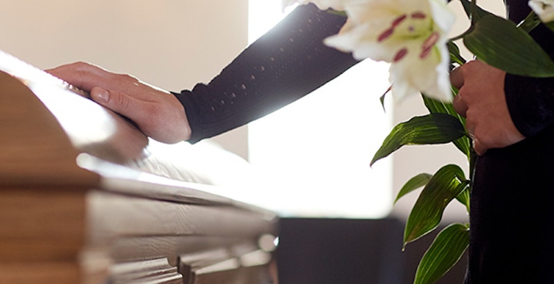 a woman placing her hand on a casket