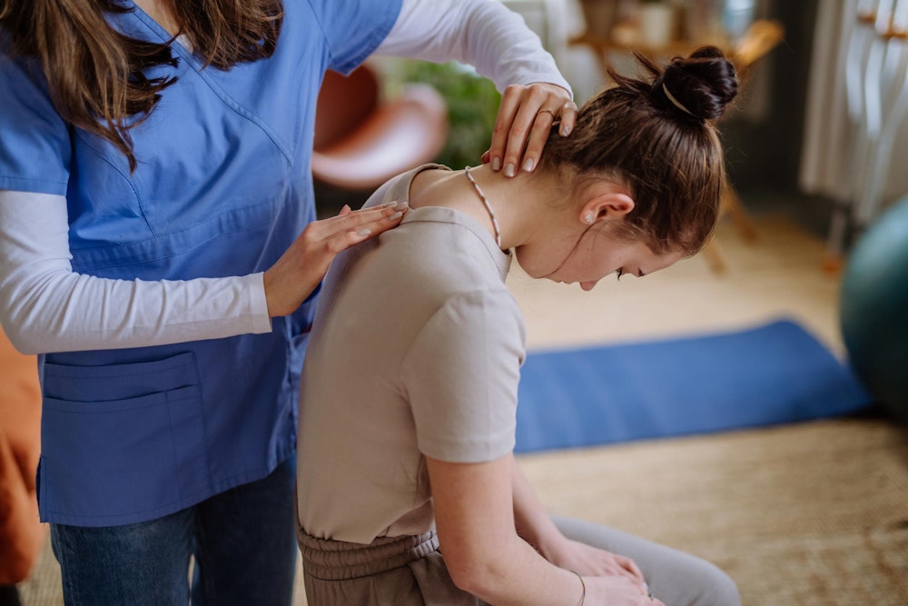Young woman having her back worked on during physical therapy