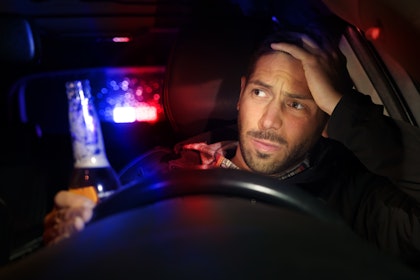 Drunk driver being pulled over with beer in his hand