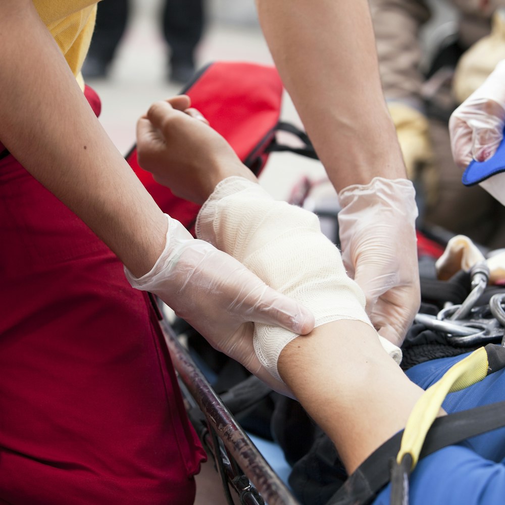 Man on stretcher receiving bandage on arm