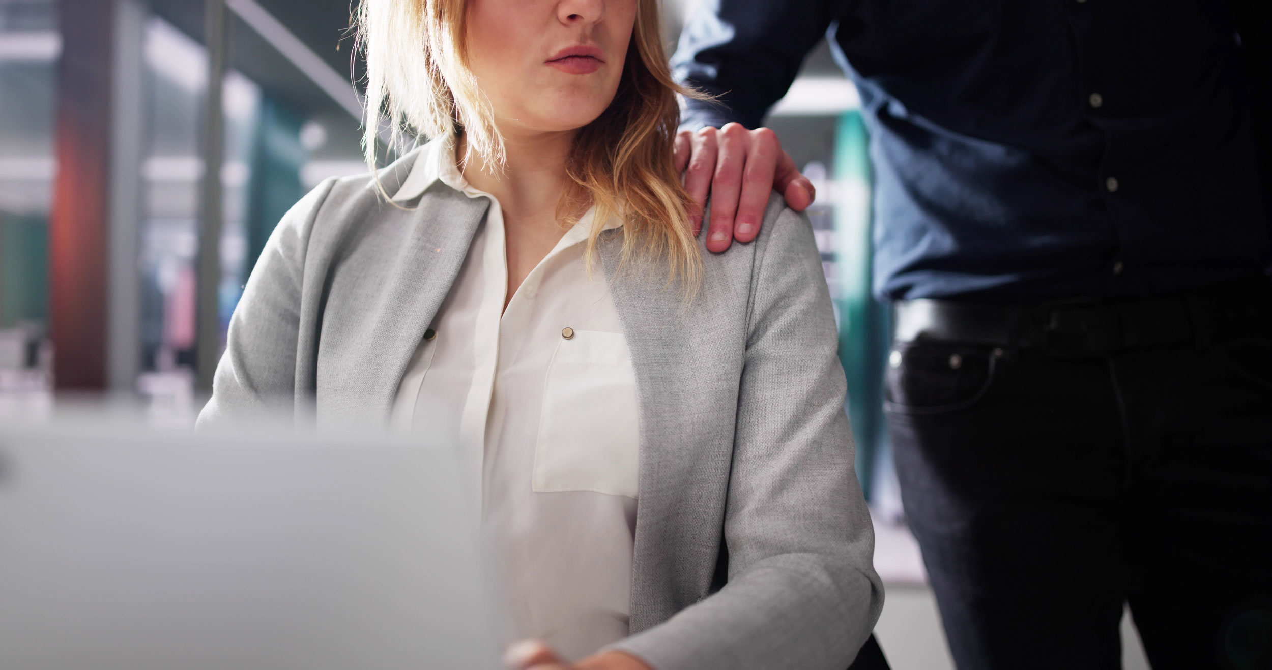 Uncomfortable woman with workplace sexual abuser's hand on her shoulder in Federal Way, Washington