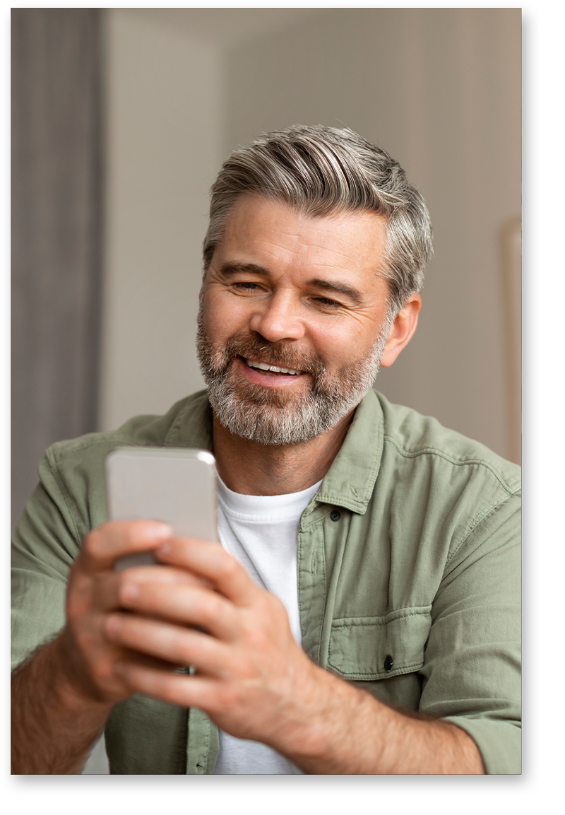 Smiling man with dentures looking at phone