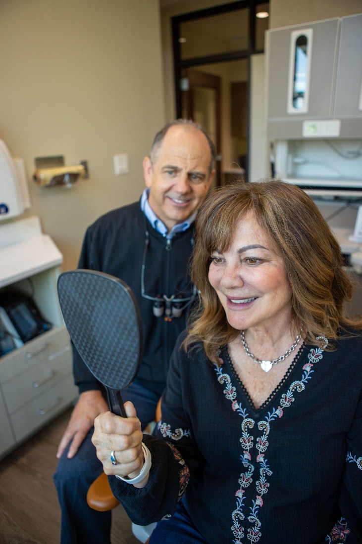 Dr. Slaman with a happy smiling patient looking in the mirror