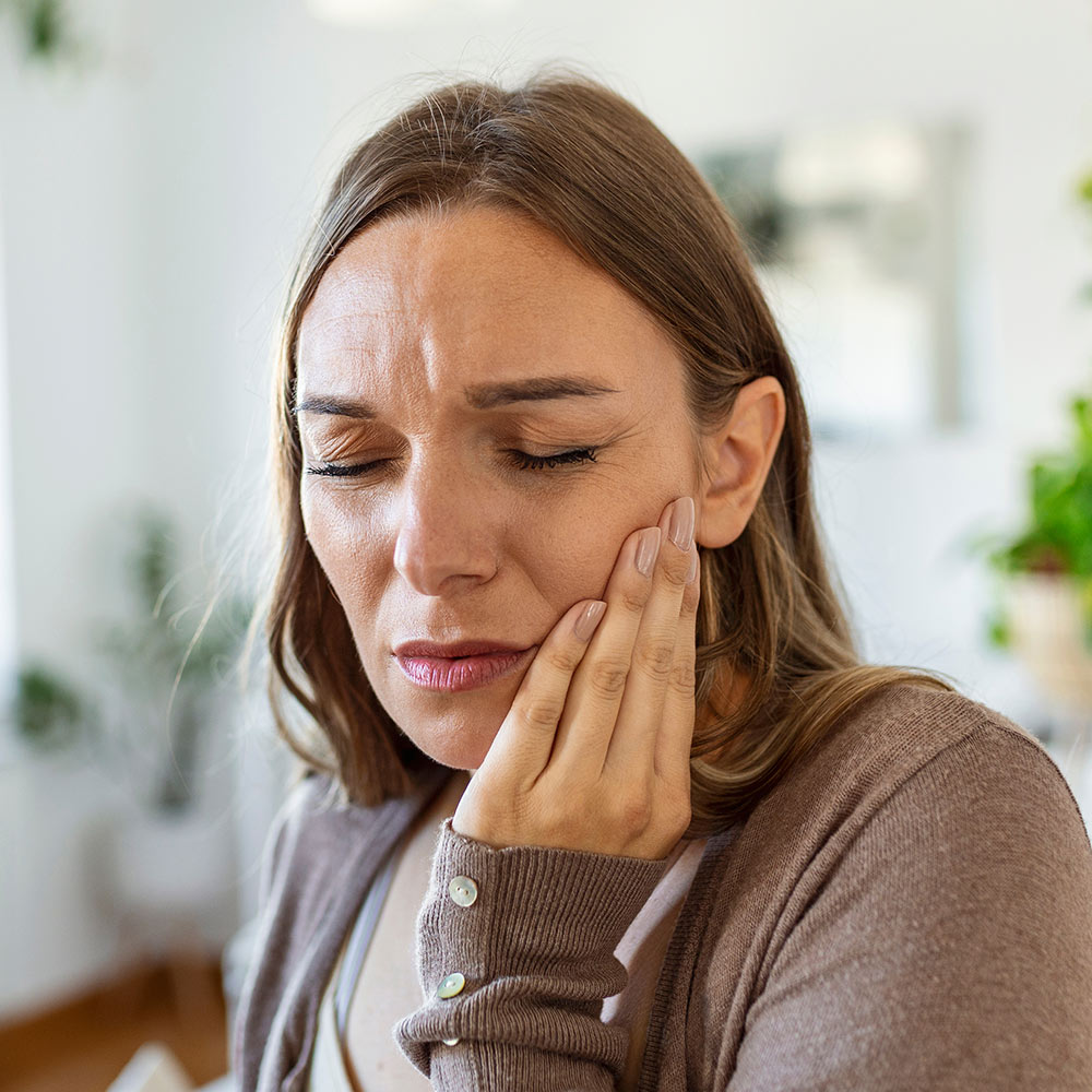 Woman holds jaw in pain