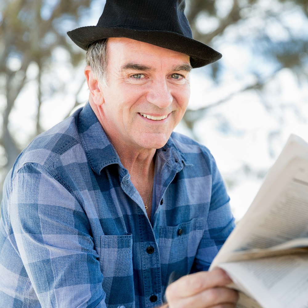 Smiling older man in hat reading outdoors