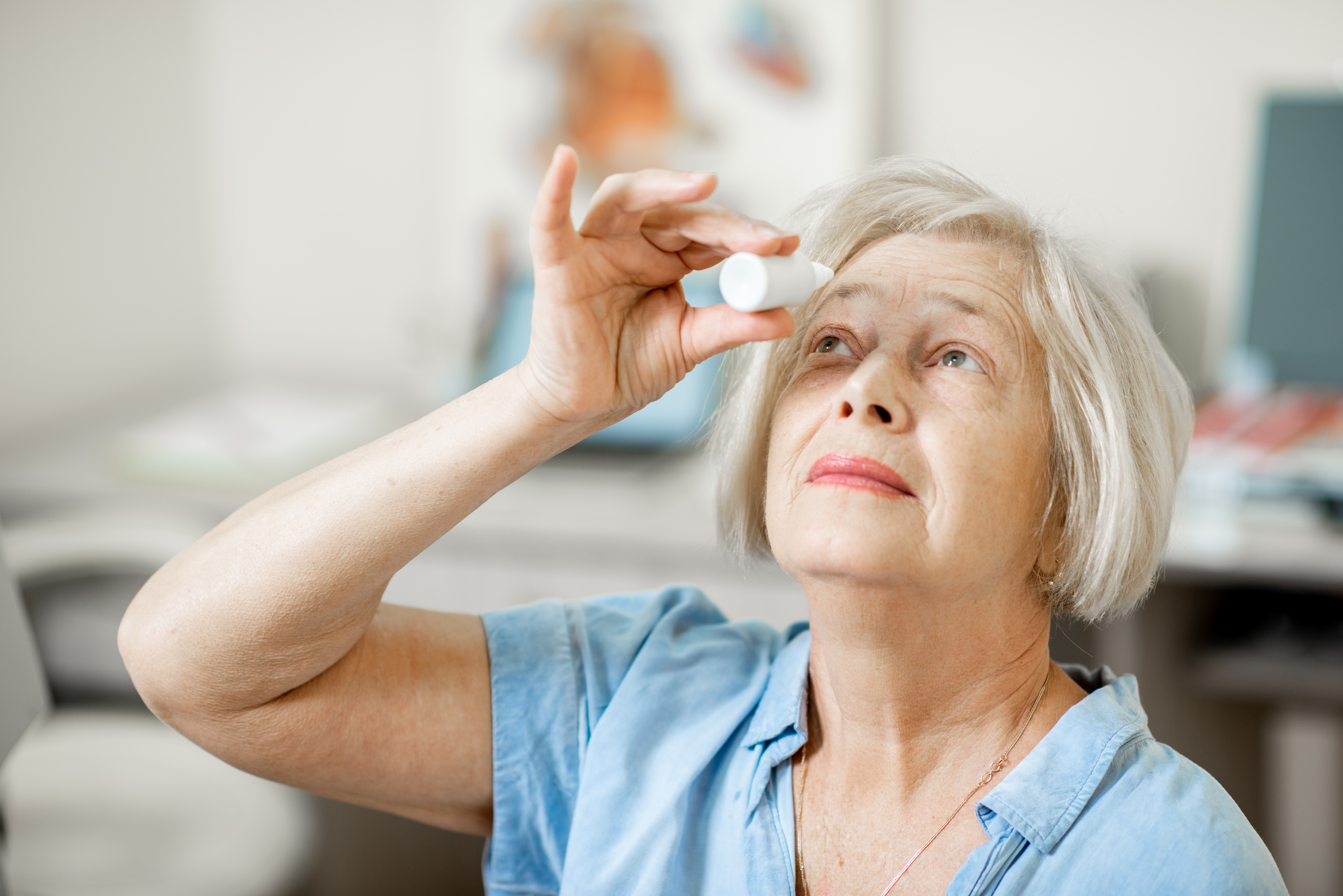 Senior woman putting in eye drops