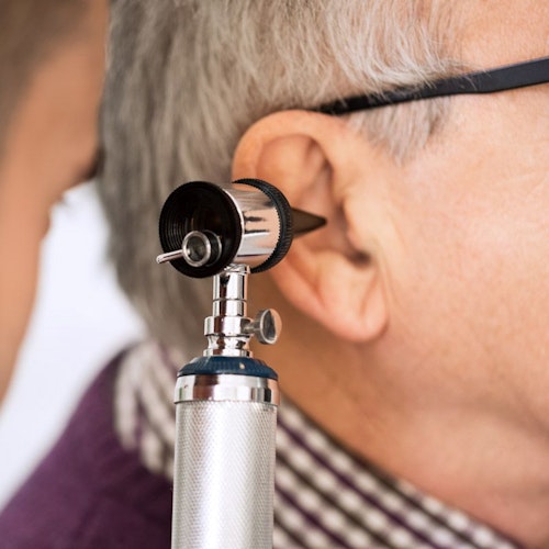 A doctor using an otoscope to examine an elderly man's ear