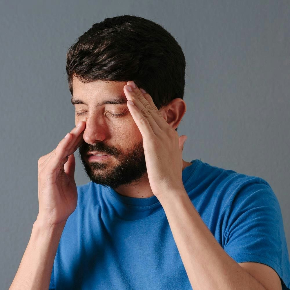 Man holding nose in pain