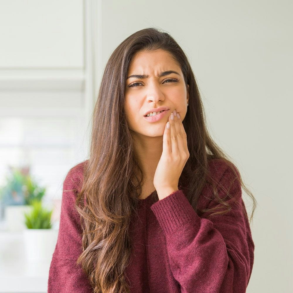 Woman frowning with hand on jaw