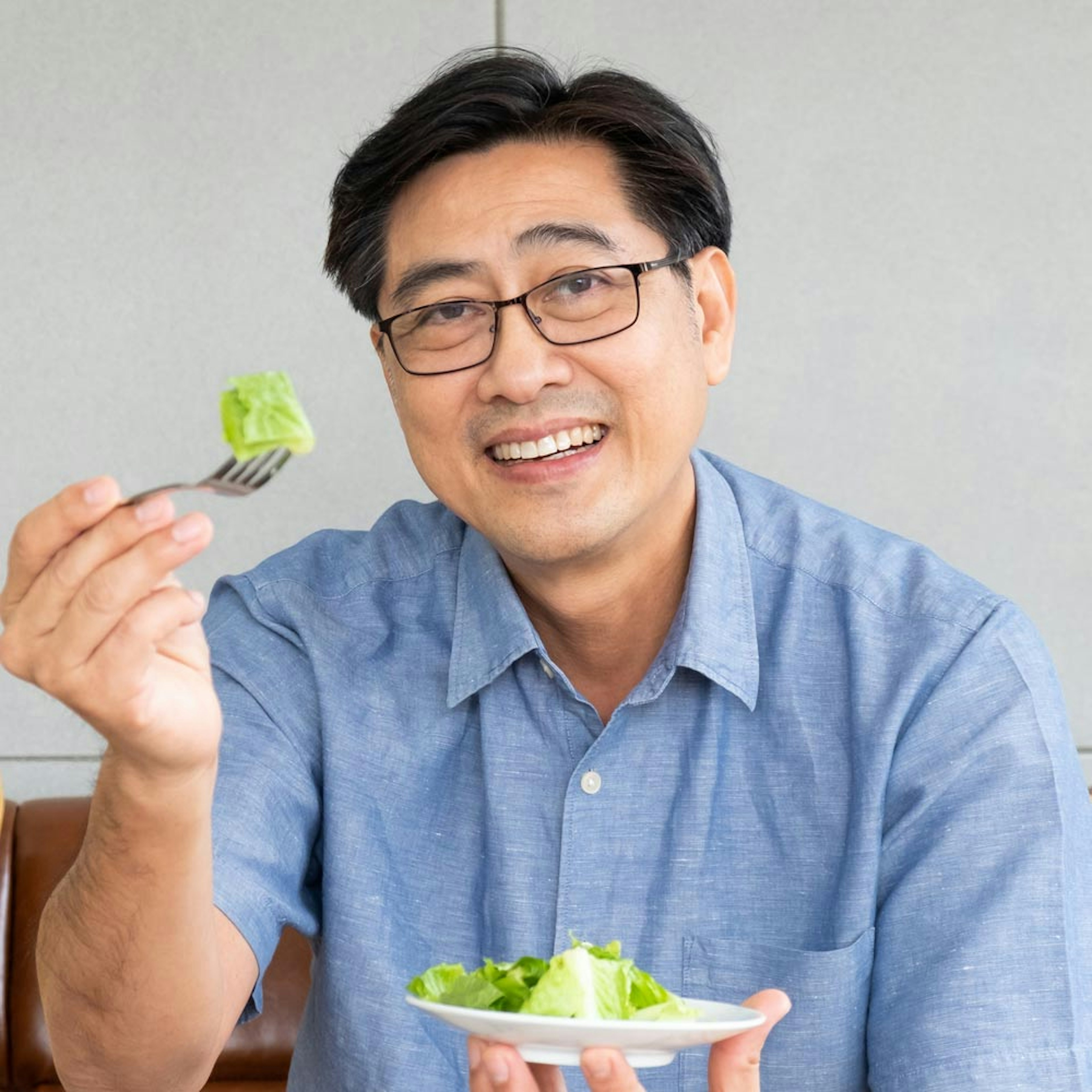 Mature man after restorative dentistry smiling while eating salad