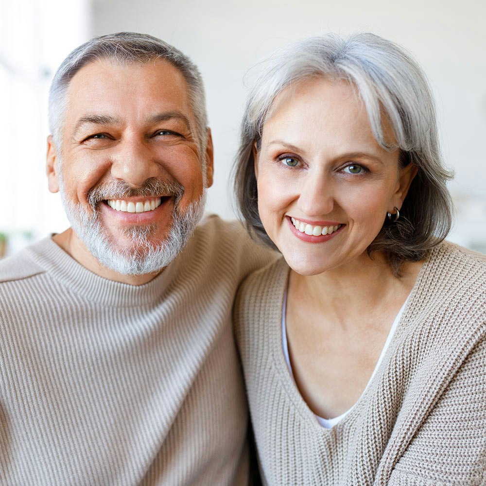 Smiling couple after dental crowns treatment