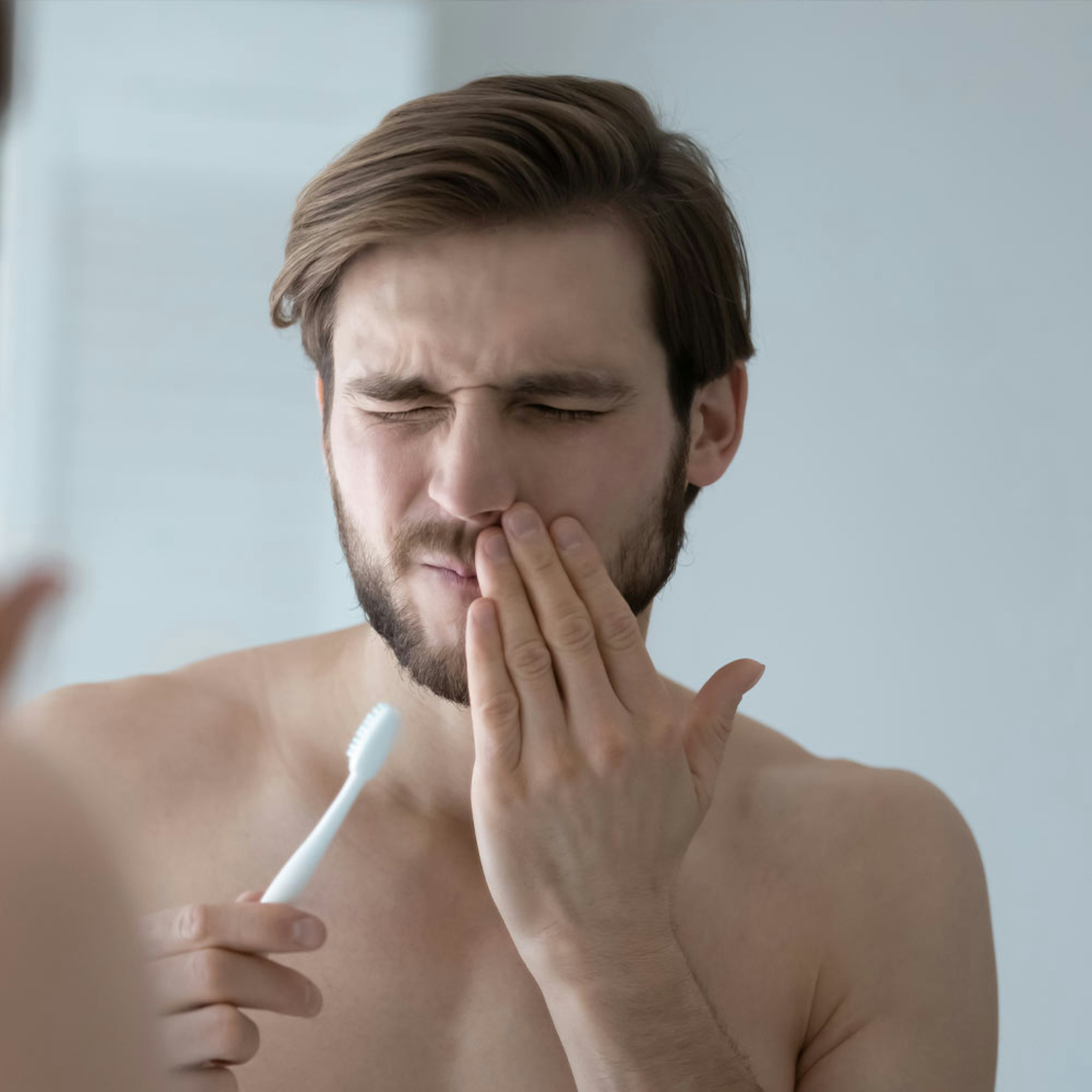 Man brushing teeth with jaw pain