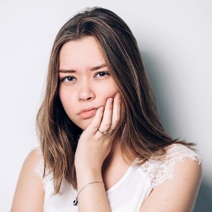 Teenage girl holding jaw in pain and in need of wisdom tooth removal