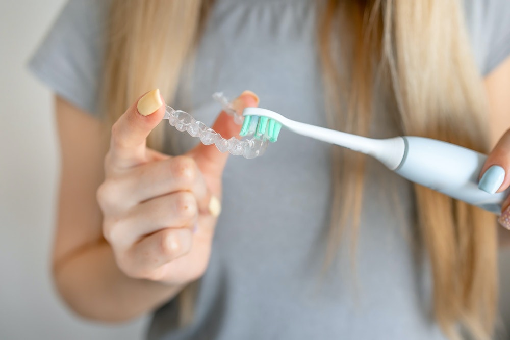 Woman brushing her invisalign tray