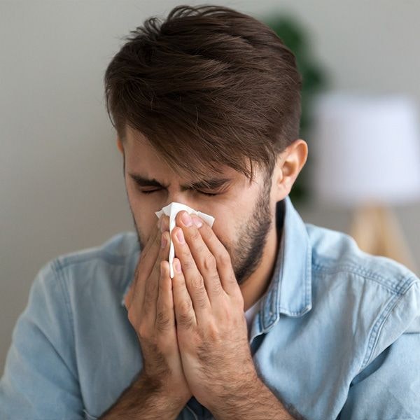 Man in need of wisdom tooth extraction blowing nose
