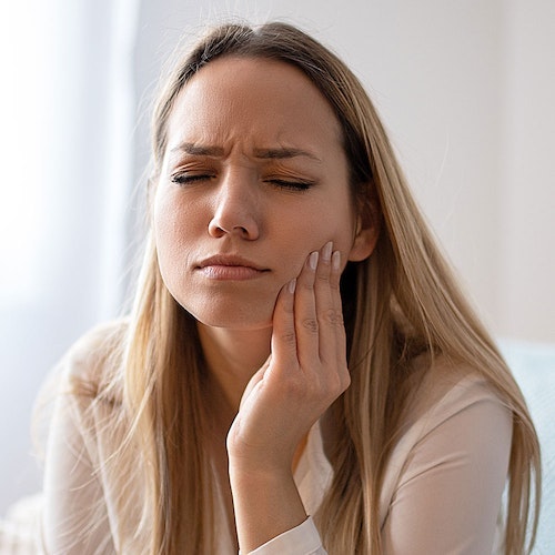 Woman holding jaw in pain and in need of wisdom tooth extraction