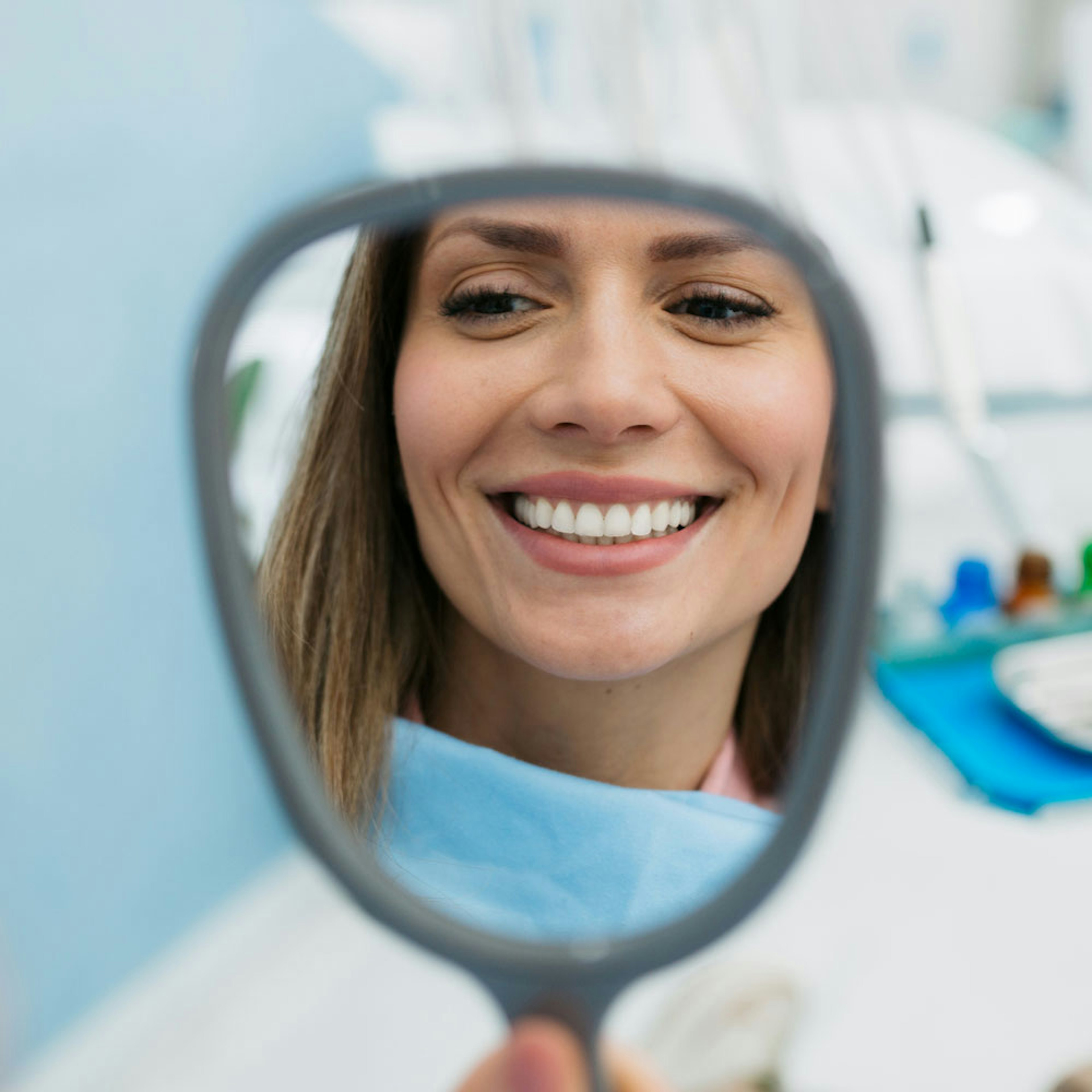 Woman smiling in mirror in dental office