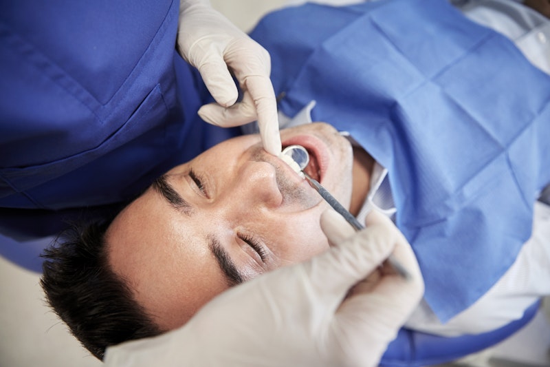 Man with dental tools in his mouth