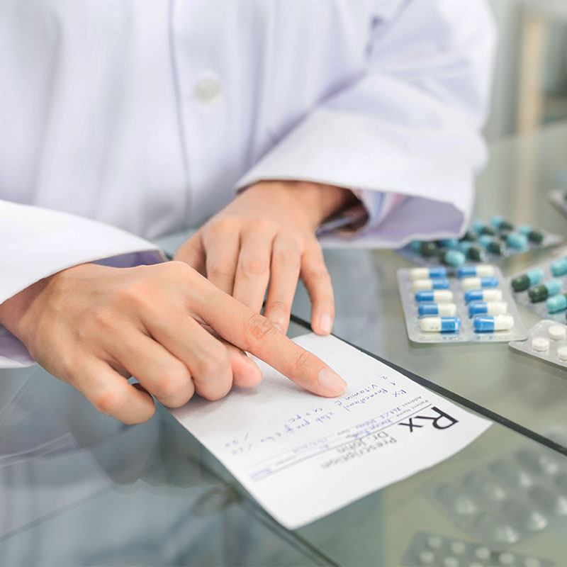Doctor looking at prescription next to pills