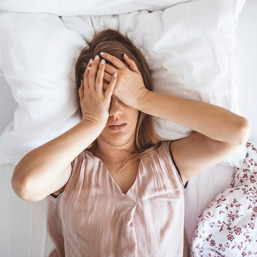 Woman lying in bed with her hands on her eyes
