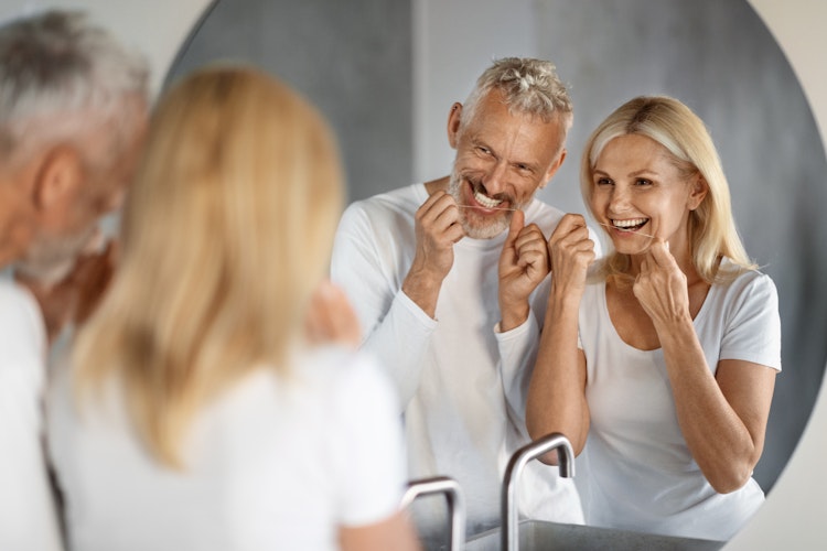 Couple smiling in the mirror while flossing