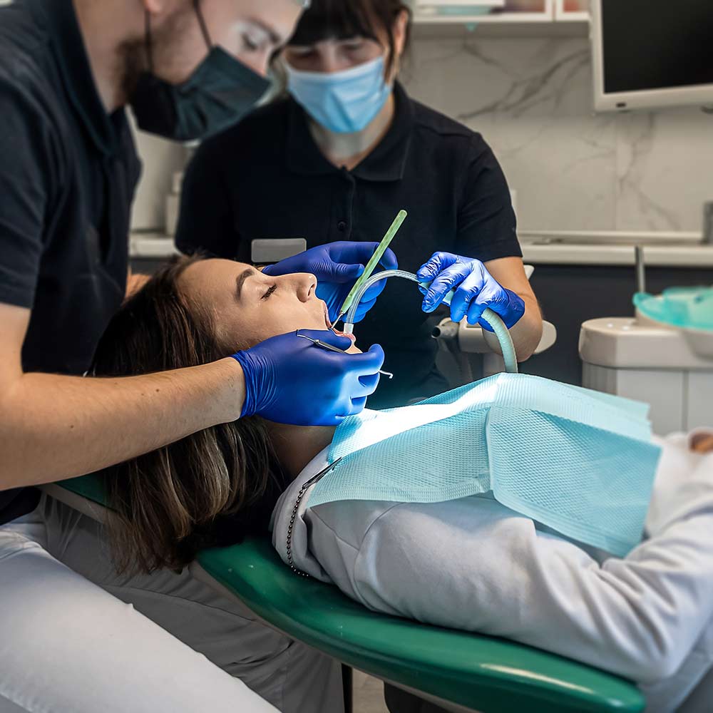 Two dental professionals in masks treating a patient in a dental chair