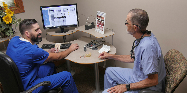 Dr. Joseph Sutton and Dr. David Sutton reviewing dental scans together at a consultation desk