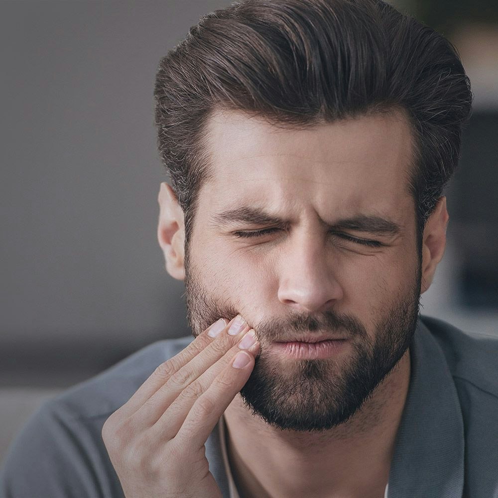 man holding his jaw in pain