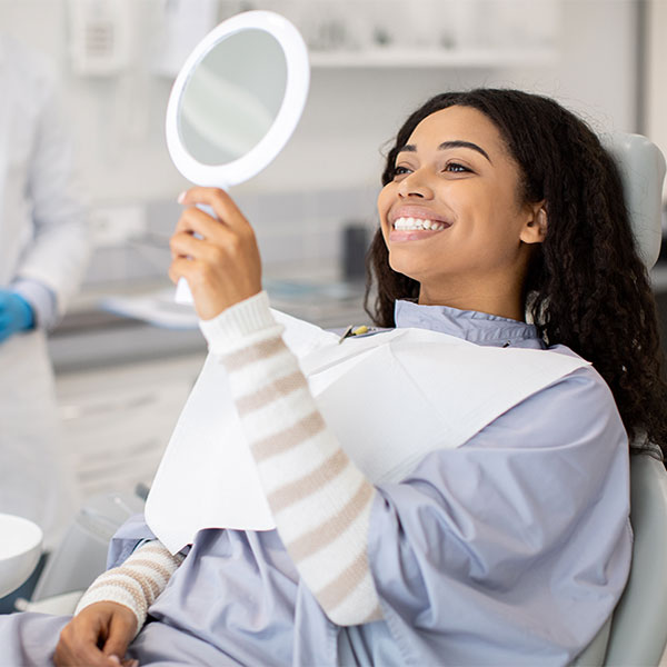 young woman smiling in a mirror at the dentist