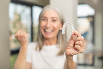 Older woman holding clear aligner