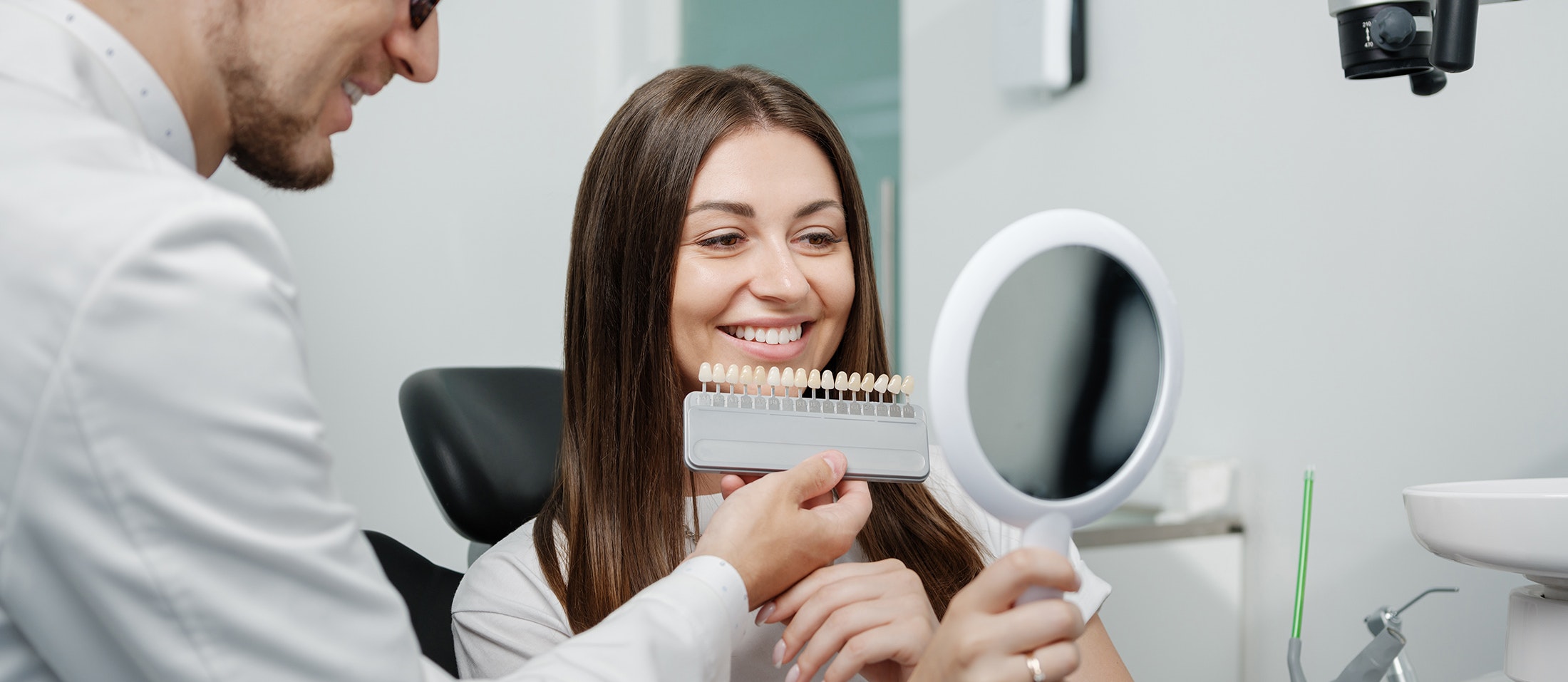 Woman smiling in mirror comparing veneers
