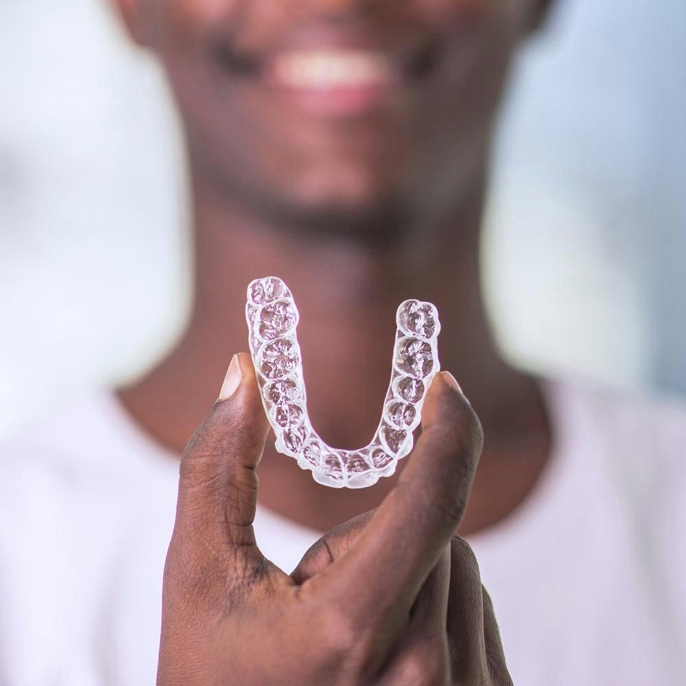 Someone holding a clear mouth aligner