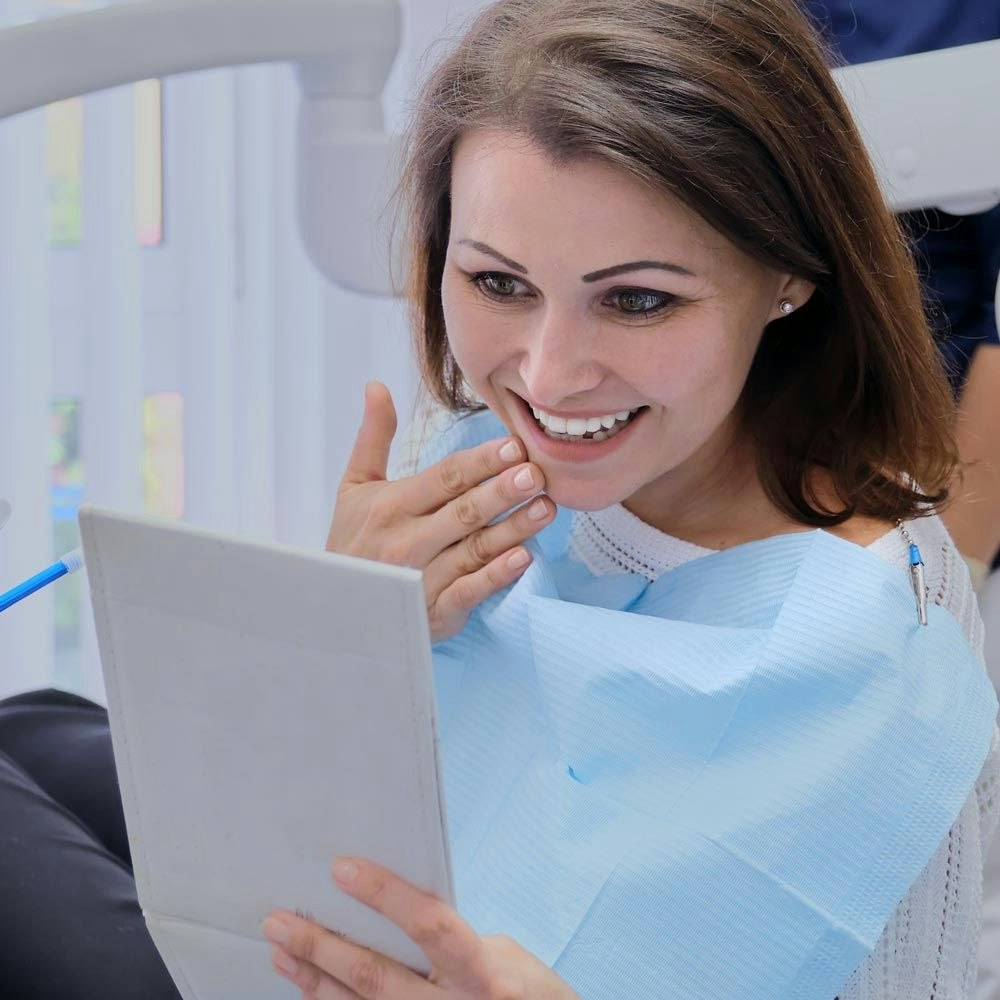 Woman in dental chair looking at iPad and smiling