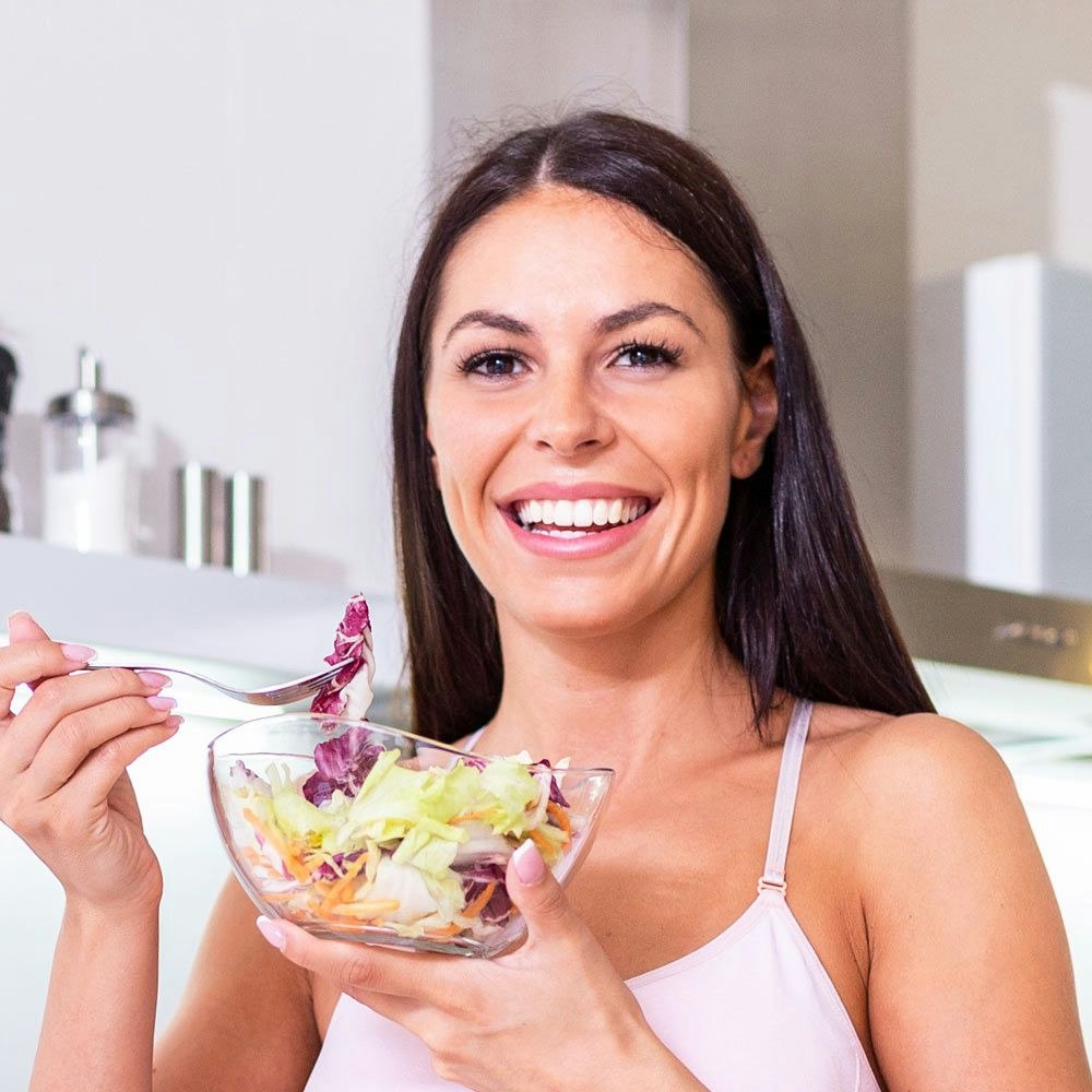 Smiling woman eating salad