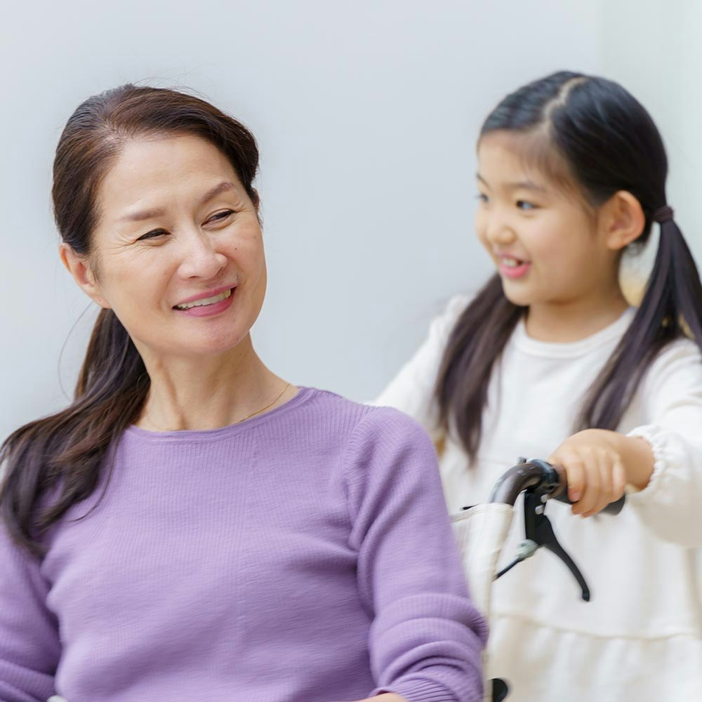 Granddaughter pushing happy grandmother in wheelchair