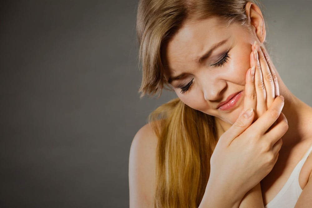 Woman clutching jaw in pain