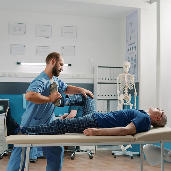 Physical therapist stretching man's leg