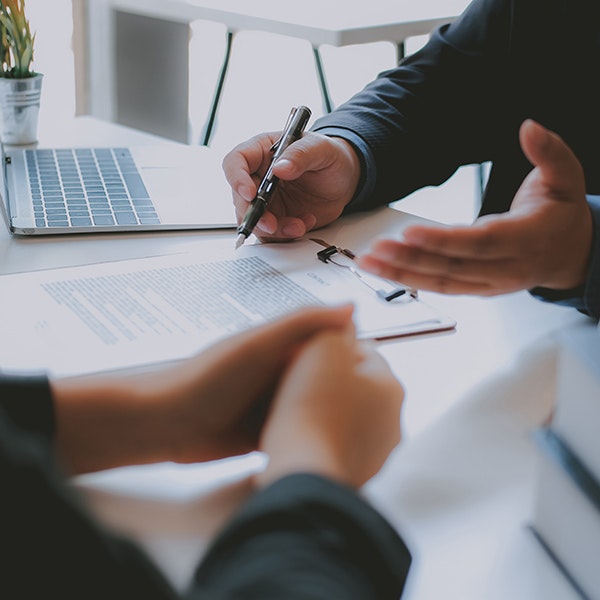Man referencing documents and speaking with coworker