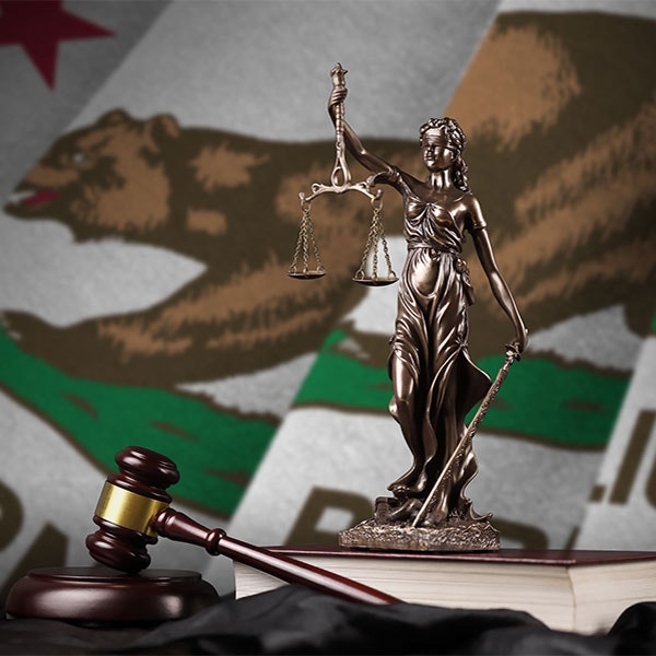 a lady justice and gavel against a California flag background