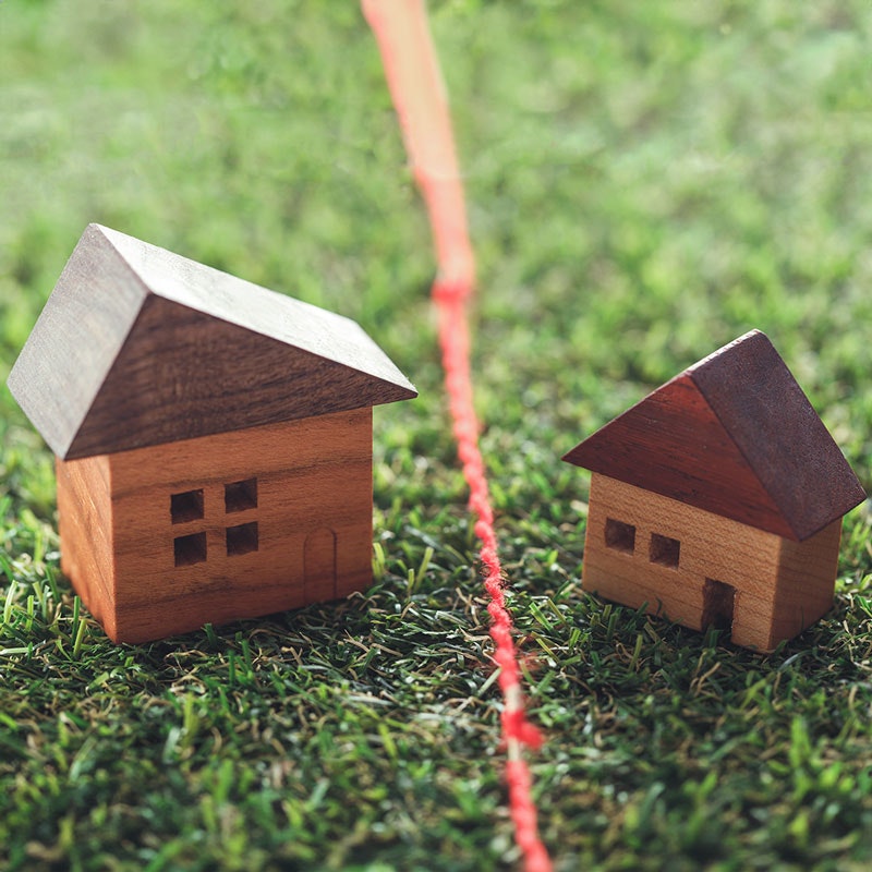 two small, wooden houses separated by a red rope