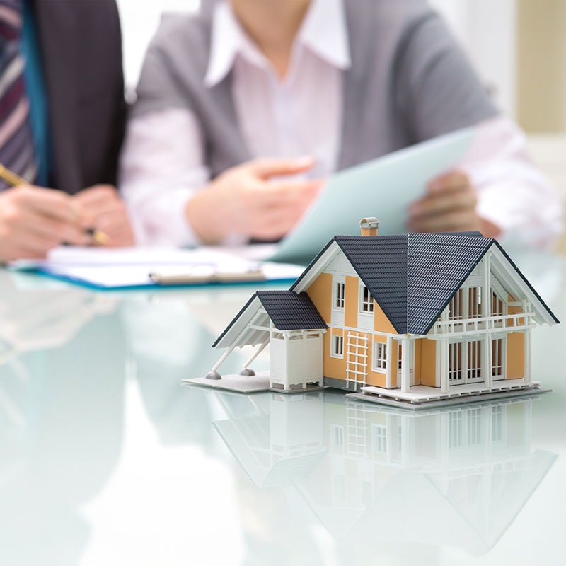 two people looking at papers behind the model of a house