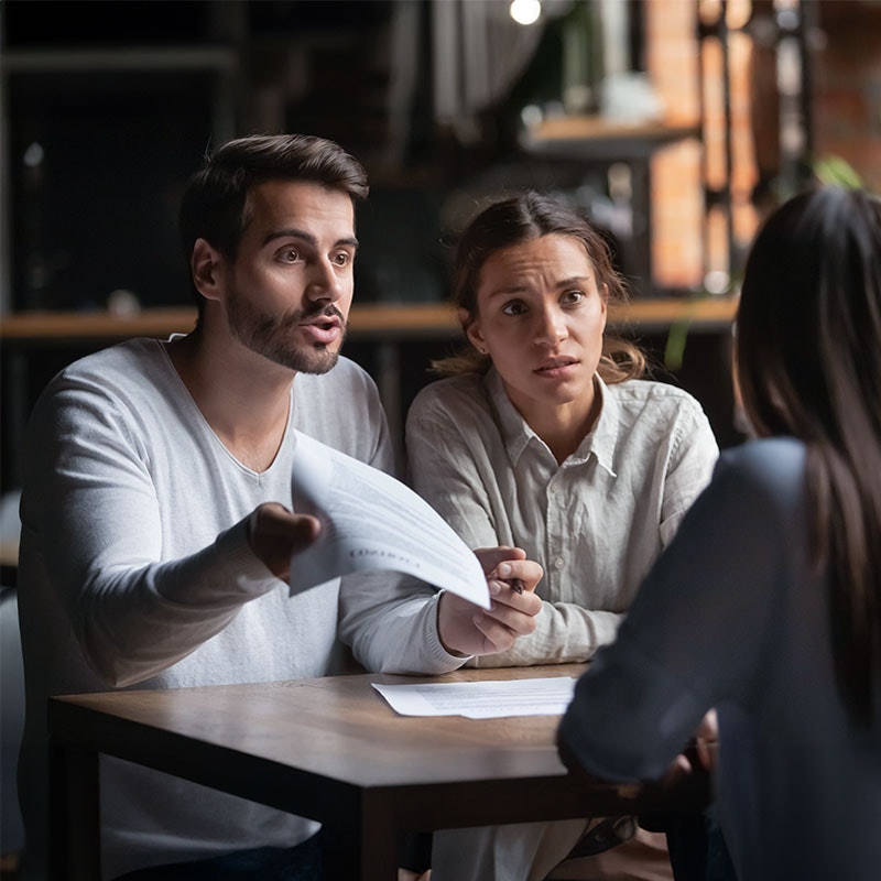 Couple arguing with business woman while showing her papers