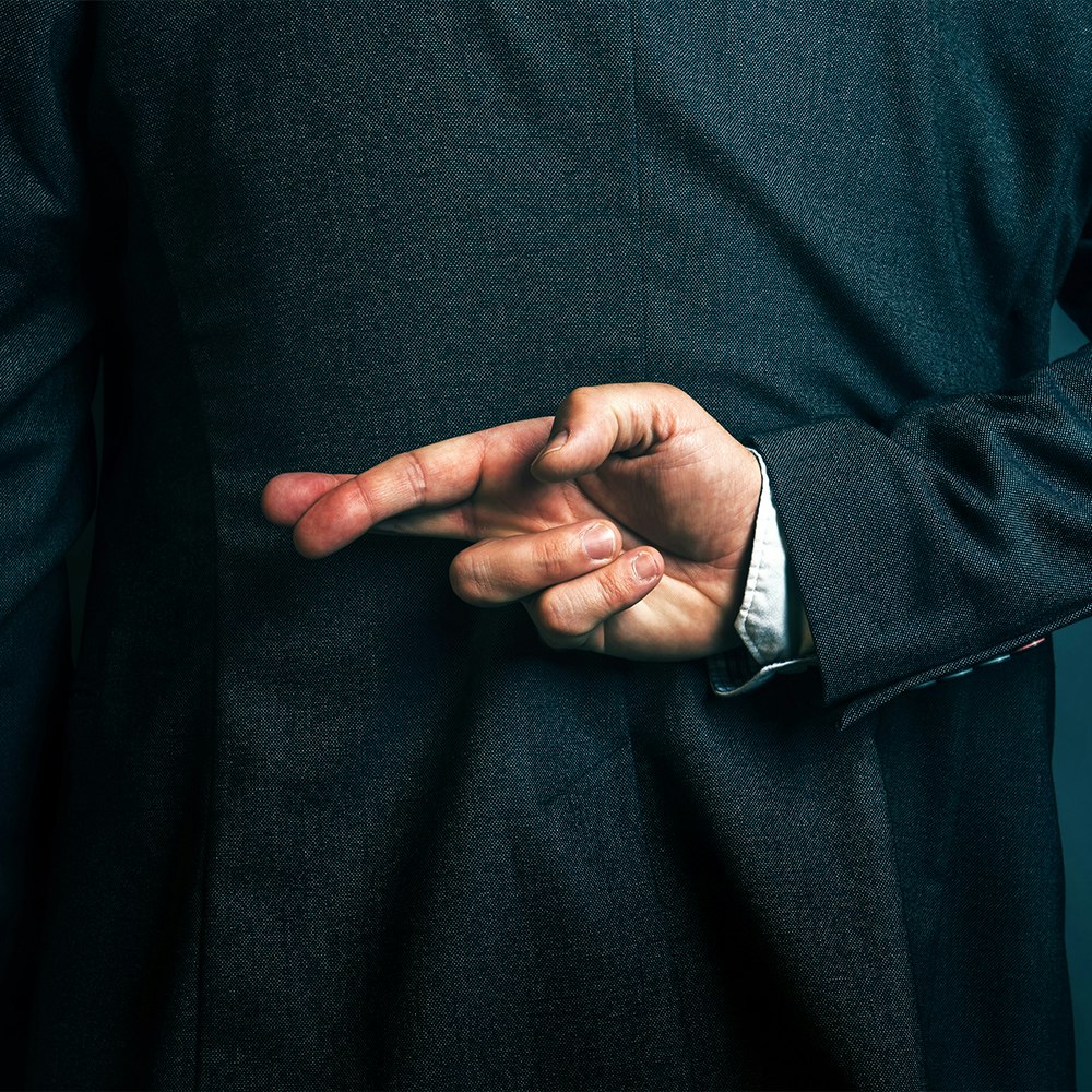 business man with fingers crossed behind back