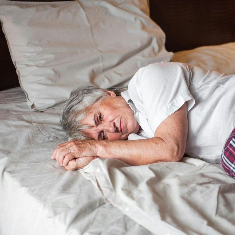 Scared elderly woman lying in bed