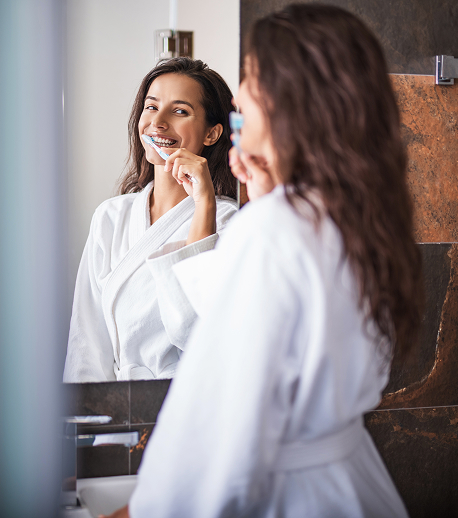 woman brushing her teeth in a mirror