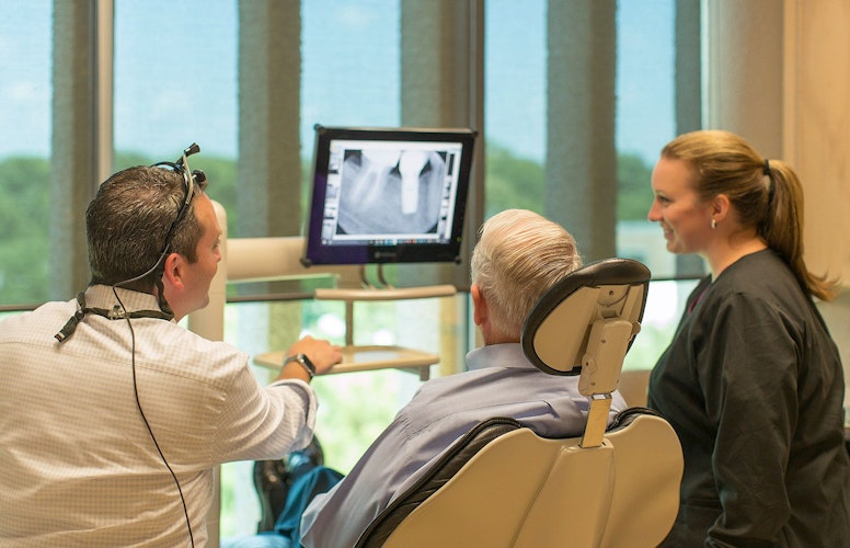 Dr. Meek reviewing a patient's x-ray of their tooth root and dental implant