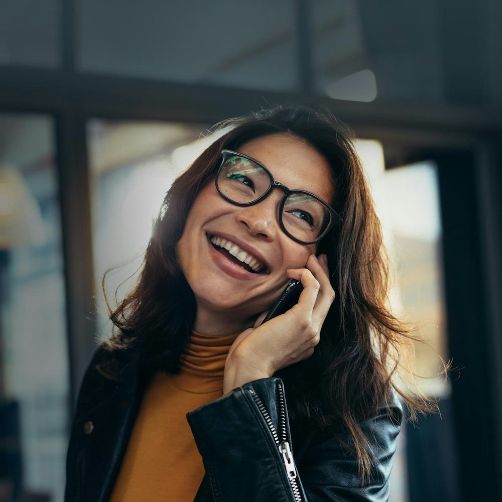 Smiling woman on phone after dental bridge placement