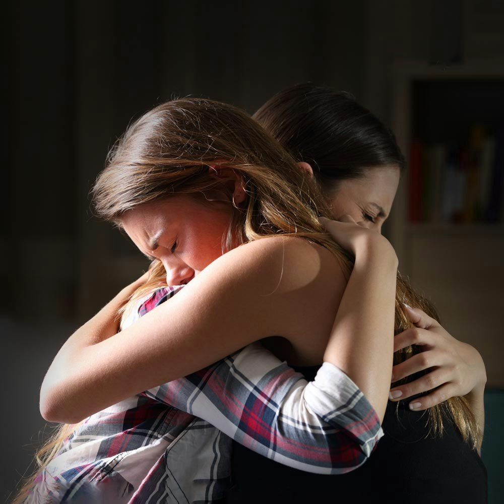 Women hugging each other as they grieve a death